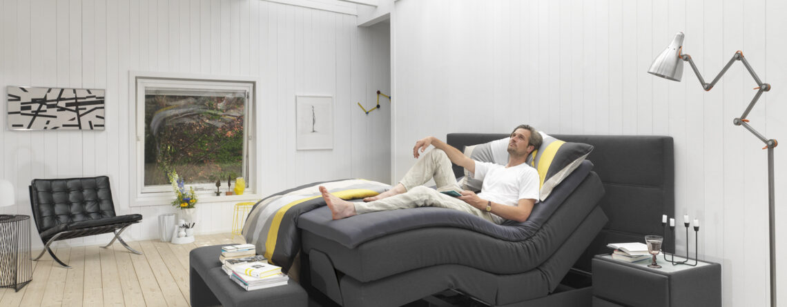 Boxspringbett Philrouge EOS inszeniert in anthrazit mit Schwarzen Füssen und mit Personen welche die Verstellbarketi demonstriert